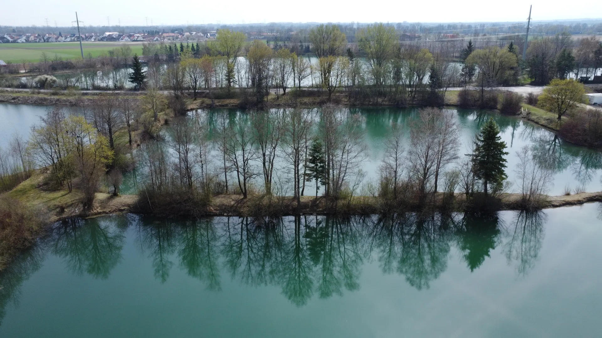 peaceful foggy lake at dawn with calm water reflecting the surrounding forest and a soft morning glow